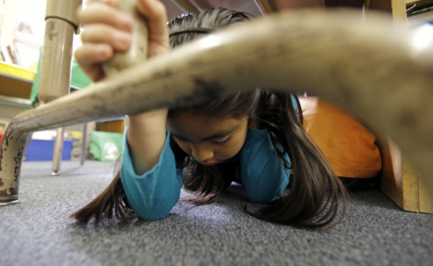Lillian Zurita shows the proper way to 'drop, cover and hold on' in Ms. Irvin's second-grade class during an earthquake drill known as the Great Shakeout at Rosemont Elementary School near downtown Los Angeles Thursday, Oct. 17, 2013.