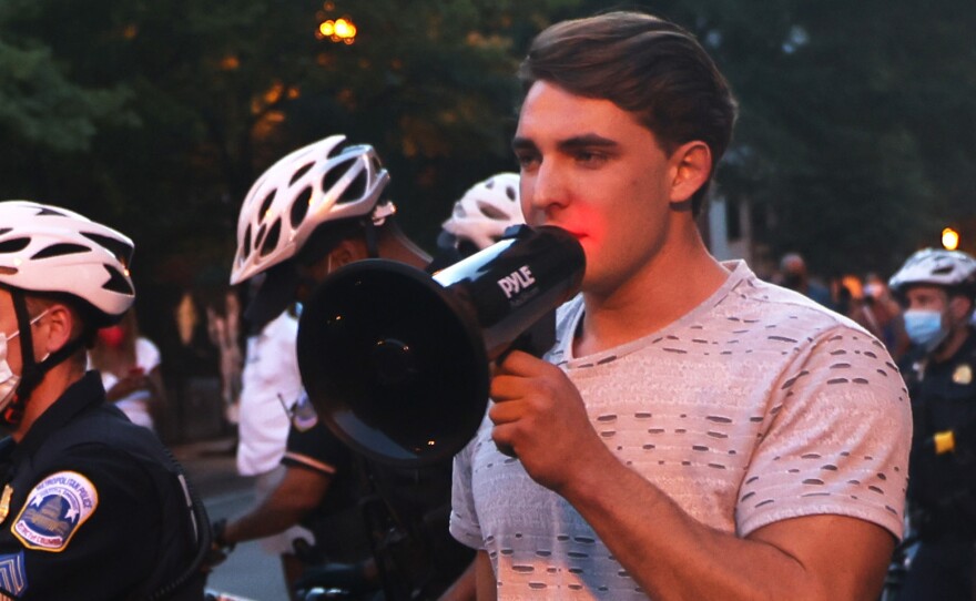 Jacob Wohl, pictured here surrounded by police officers at a 2020 protest in Washington D.C., is one of two right-wing activists who were behind a 2020 robocall scheme that targeted minority voters. Wohl will now face probation, fines and 500 hours of voter registration assistance for pleading guilty to telecommunications fraud.