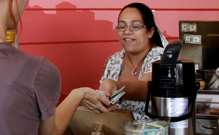 Carmen Castillo, an employee of Café de Leche, gives change back to a customer.