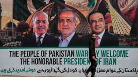 A man walks past a welcoming billboard featuring Iranian President Masoud Pezeshkian, center, with Pakistan President Asif Ali Zardari, right, and Shehbaz Sharif along a roadside in Islamabad, Pakistan, Tuesday, June 23, 2026.