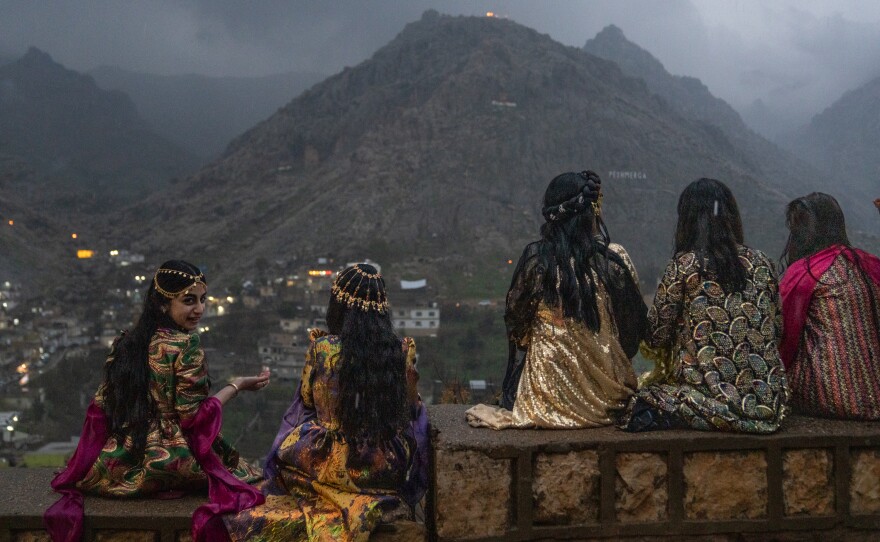 Girls sit on a wall to get a good vantage point of people walking up the mountains with flaming torches and fireworks for Nowruz in Akre, the Kurdish region of Iraq on Friday.