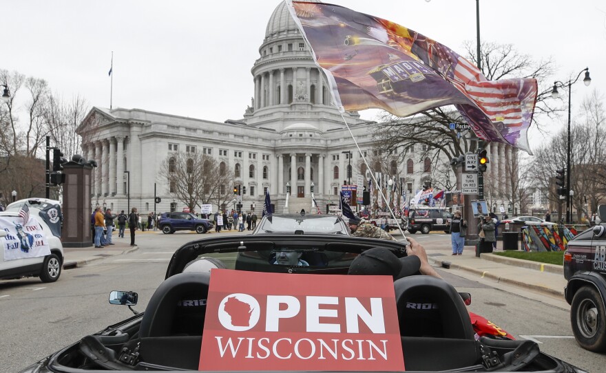 People in cars participate in a protest against the coronavirus shutdown in front of the state capitol in Madison, Wisc., on April 24, 2020.