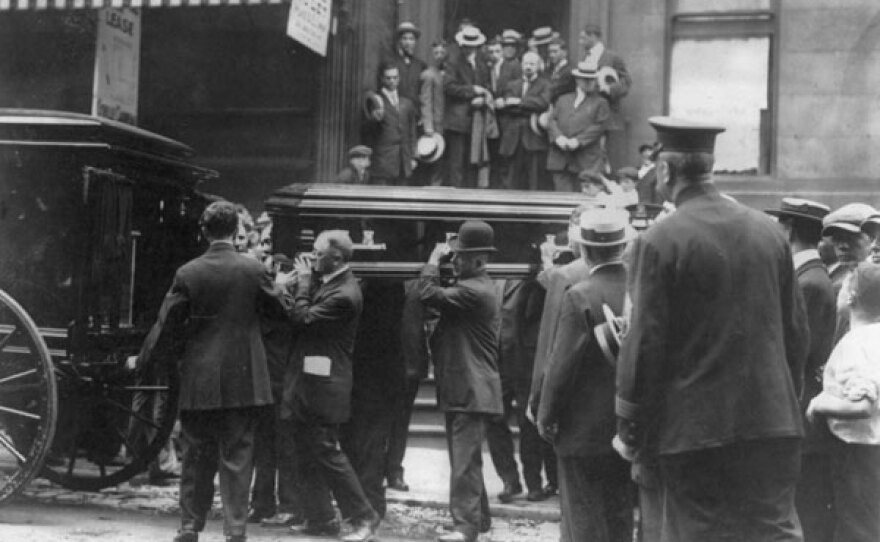 Men load a coffin into a hearse.