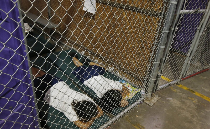 FILE - Two female detainees sleep in a holding cell, as the children are separated by age group and gender, as hundreds of mostly Central American immigrant children are being processed and held at the U.S. Customs and Border Protection Nogales Placement Center on Wednesday, June 18, 2014, in Nogales, Ariz.
