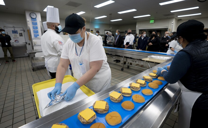 Workers prepare burgers for hundreds of migrants female teenagers set to arrive at the San Diego Convention Center Saturday night, March 27, 2021.