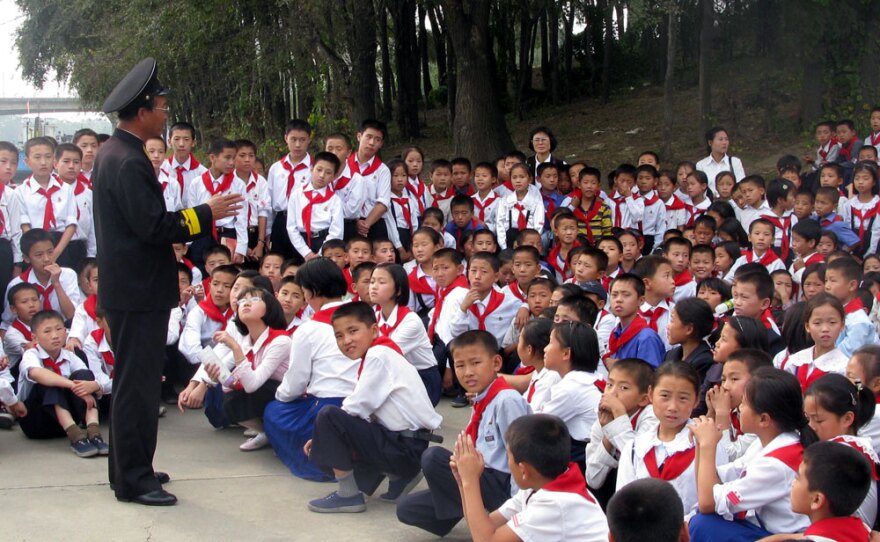On the wharf beside the Pueblo, schoolchildren listen to a lecture by one of the first North Korean sailors to board and capture the ship.