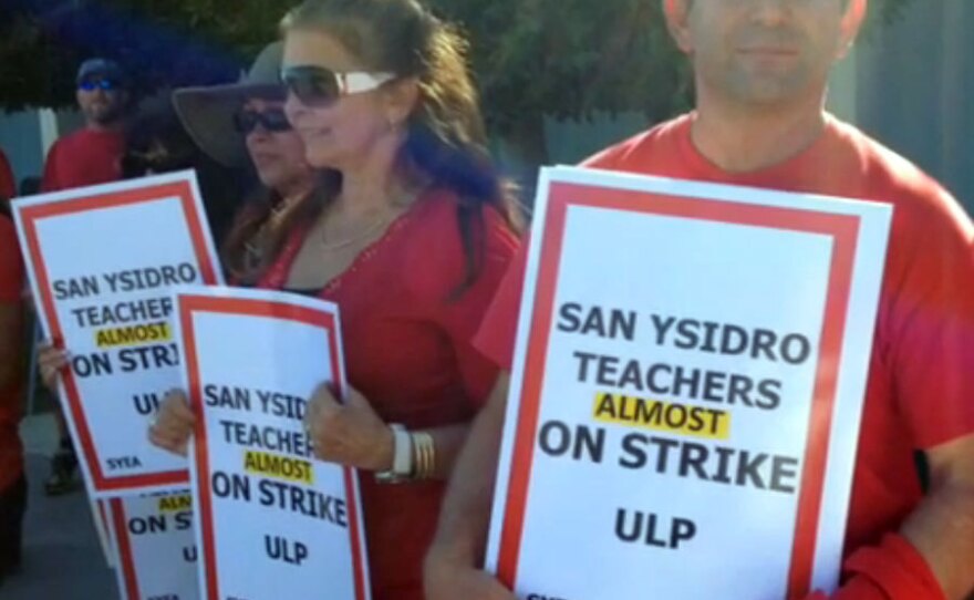 San Ysidro teachers hold signs that read "San Ysidro Teachers Almost on Strike."
