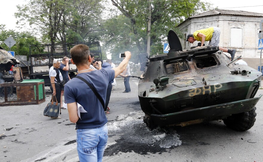 Local residents examine  destroyed vehicles at the site of fighting after Ukrainian forces recaptured the city from pro-Russian separatists on Friday.