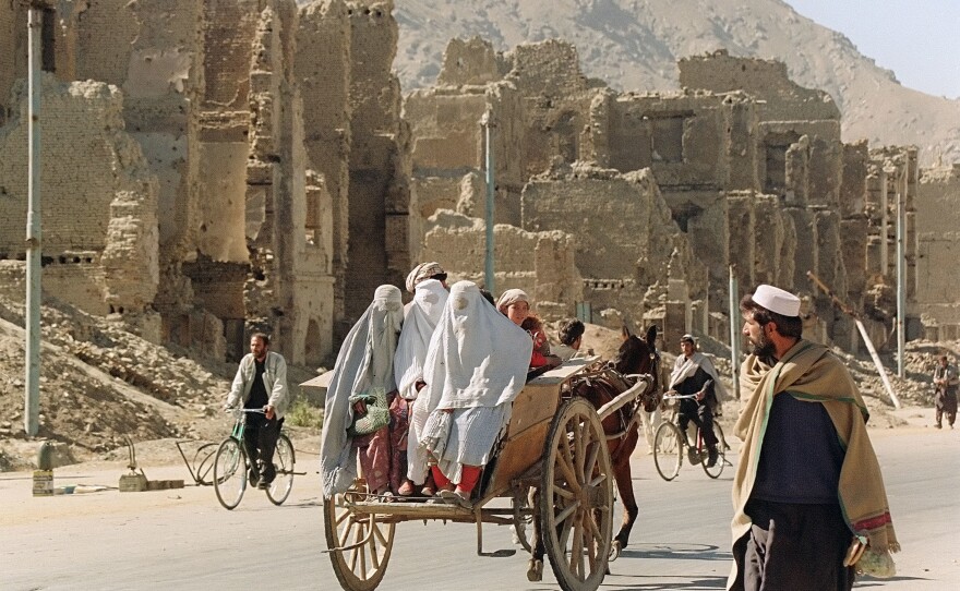 Past the ruins of Kabul's former commercial district, three women ride on the back of a donkey cart in November 1996, two months after the Taliban took control of the war-ravaged city.
