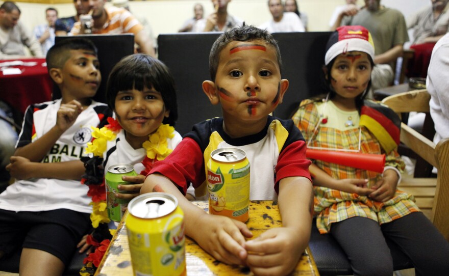 Young fans of the German national soccer team drink iced tea in July 2010 as they watch the FIFA World Cup semi-final match Germany vs. Spain in an Arabic cafe in Berlin's Neukölln district. The neighborhood has gentrified rapidly in recent years, but many of the white families moving in leave once their children reach school age. Local groups are trying to change that.
