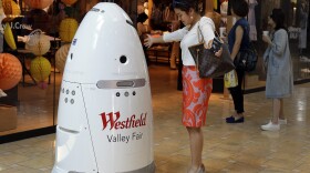 Sophie Li, of Cupertino, Calif., offers to dance with a K5 robot made by Knightscope, Inc., at Westfield Valley Fair shopping center in San Jose, Calif., June 26, 201. 