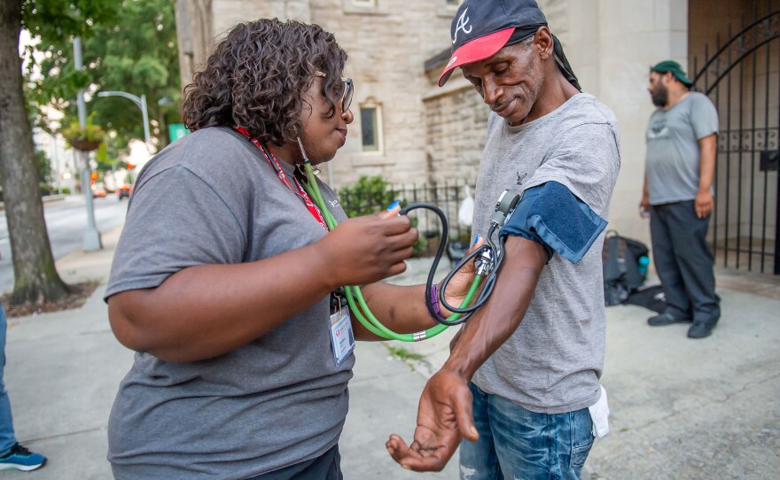 Licensed practical nurse Stephanie Dotson measures Kent Beasley's blood pressure in downtown Atlanta in September. Dotson is a member of the Mercy Care team that works to bring medical care to Atlanta residents who are homeless.