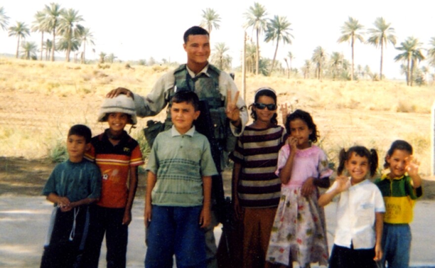 Jason Poole takes a photo with children in Iraq during the war.