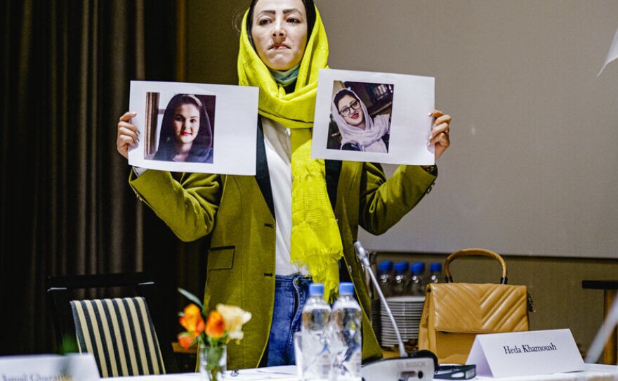 Delegate from the Afghan civil society Heda Khamoush holds up photos of two women who have vanished, ahead of a meeting, in Oslo, Norway, Monday, Jan. 24, 2022.