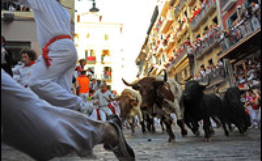 Runners flee bulls on a corner of a cobbled street in Pamplona, Spain, during the first day of the San Fermin running of the bulls fiesta. The ritual, repeated eight consecutive mornings during the festival, was made famous by Ernest Hemmingway's novel <em>The Sun Also Rises</em>.