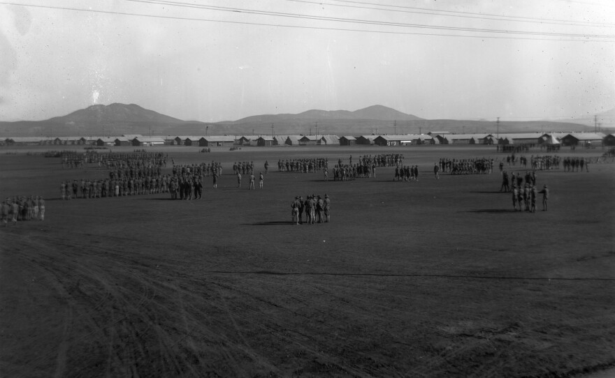 A wide black and white photo of the mesa at Camp Kearny with soldiers scattered in the foreground and a number of buildings in the distance.