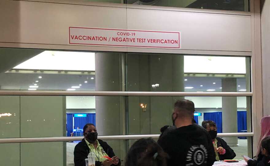 This year, attendees will need to wait in two separate lines for badges. One to prove vaccination status or negative COVID-19 test and receive a wristband, and then another in Hall H to actually get badge. Note there are far fewer staff at vaccination table than inside Hall H. Nov. 23, 2021.