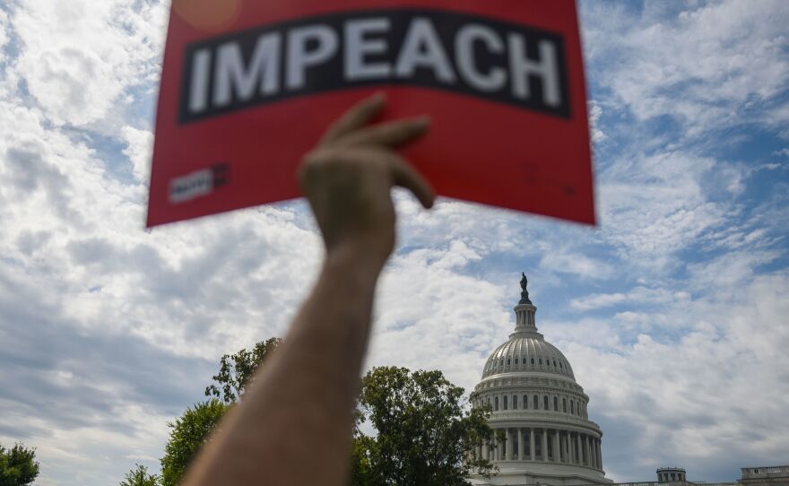 A protester holds up a sign in favor of impeachment outside the U.S. Capitol building on Thursday.