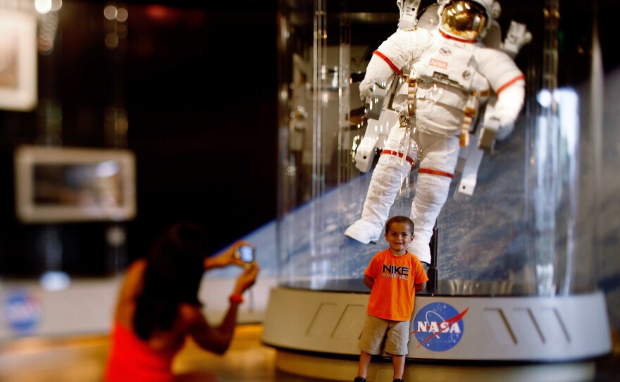 A child poses for a picture in front of an astronaut space suit at the Kennedy Space Center on the eve of the launch of Space Shuttle Endeavour July 14, 2009 in Cape Canaveral, Fla.