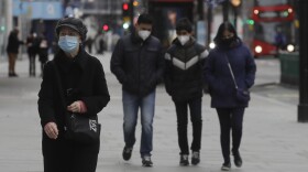 Pedestrians wear masks as they walk on Oxford Street in London, Saturday, Dec. 26, 2020.