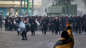 A protester in Cairo gestures to anti-riot police in front of the l-Istiqama Mosque in Giza on Friday as tens of thousands of demonstrators filled the streets.