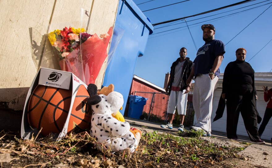 Antwan Burns-Jones, 31, left, William Moore, 35, and David Lee, 23, add a basketball to the memorial for Tyshawn Lee, 9, who was fatally shot in Chicago's Gresham neighborhood.