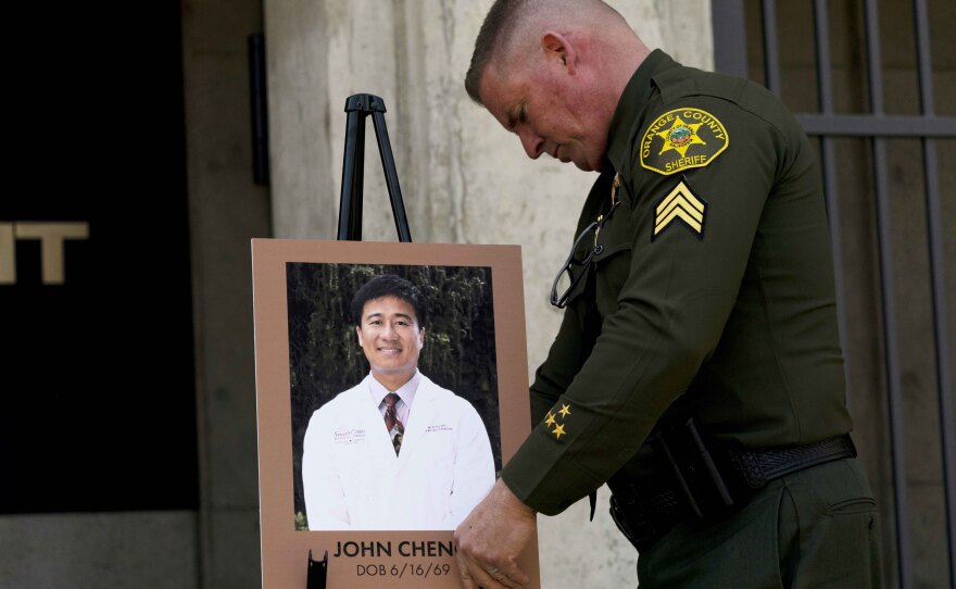 Orange County Sheriff's Sgt. Scott Steinle displays a photo of Dr. John Cheng, a 52-year-old victim who was killed in Sunday's shooting at Geneva Presbyterian Church.