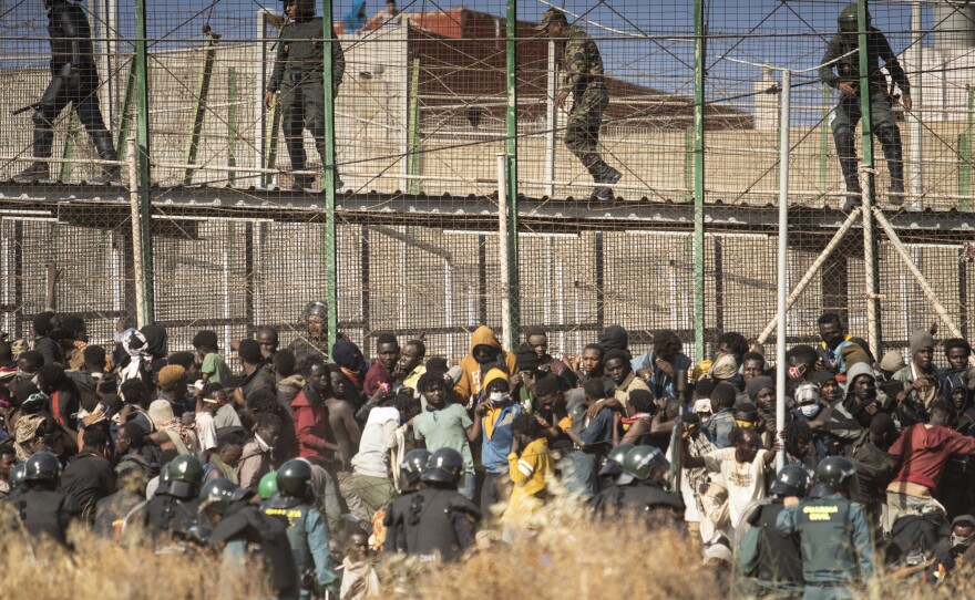 Riot police officers cordon off the area after migrants arrive on Spanish soil and crossing the fences separating the Spanish enclave of Melilla from Morocco in Melilla, Spain, Friday, June 24, 2022.