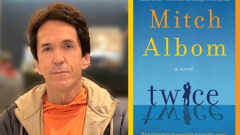 The image is an undated photograph of author Mitch Albom and shows the book cover for his novel "Twice."