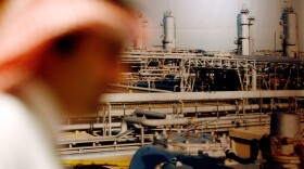A Saudi official stands in front of a giant Saudi oil industry picture at a hotel in the Red Sea port city of Jiddah, Saudi Arabia, ahead of a major oil summit in June 2008.
