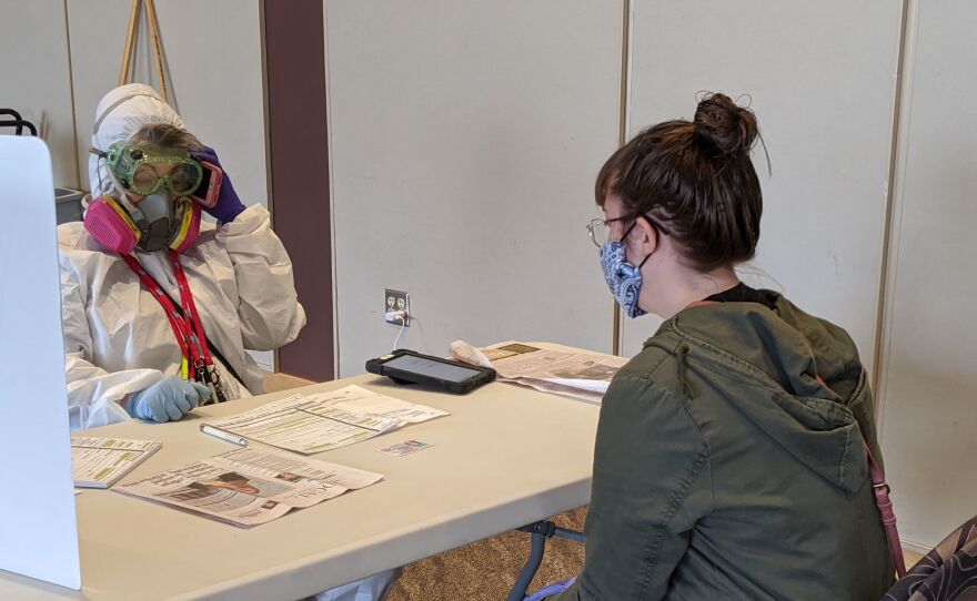 An election official in Kenosha, Wis., with a voter on April 7. Nearby Milwaukee says it's recorded at least seven coronavirus cases related to the state's controversial decision to move forward with in-person voting.