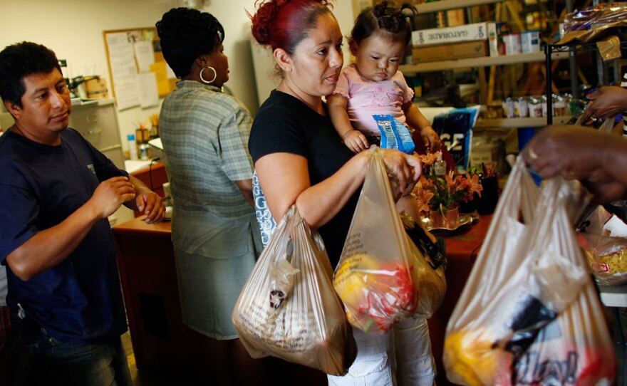 Abran Lopez (left), who was laid off from his job as a landscaper, and Angelina Martinez, who lost her construction job, receive groceries from a food co-op in Fort Lauderdale, Fla., in April 2009.