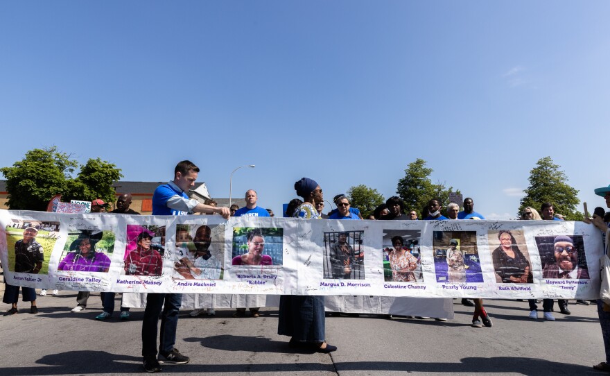 People participating in a March For Our Lives event pause at a memorial to the dead at Tops supermarket on June 11, 2022.