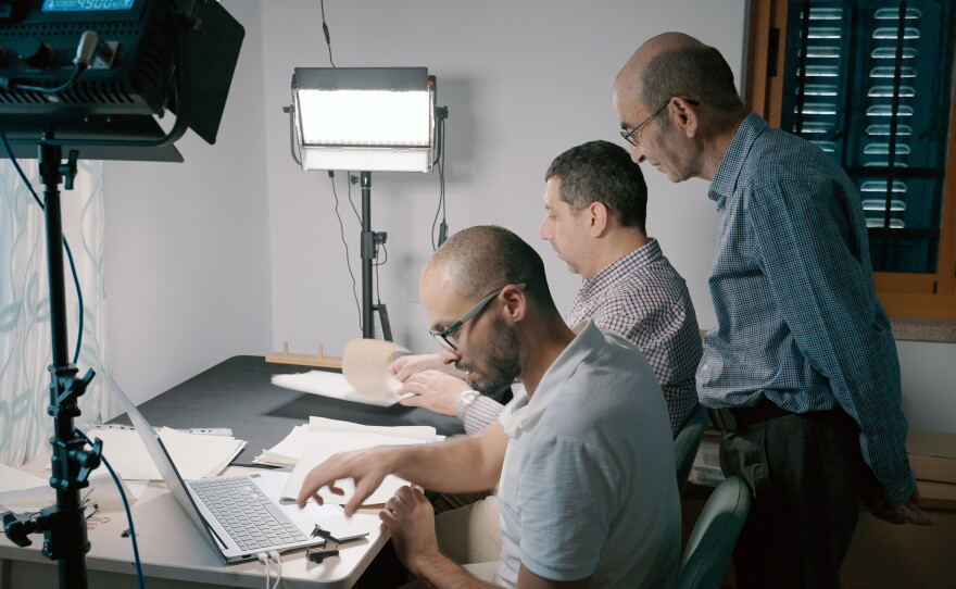 Yazeed Abu Khdeir (left) and Mahmoud Muna work to digitize papers, as Raja Shehadeh (standing) looks on.