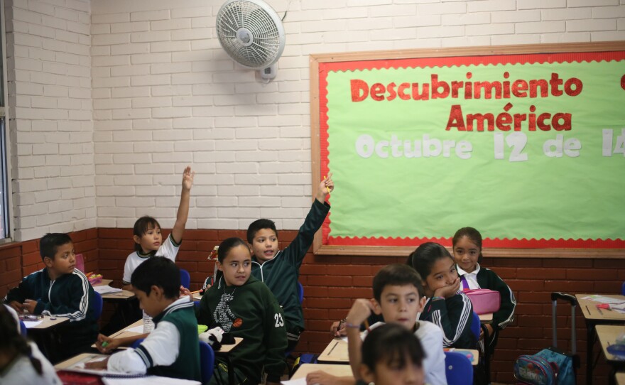 Students raise their hands at the Escuela 20 Noviembre school in Tijuana, Mexico.