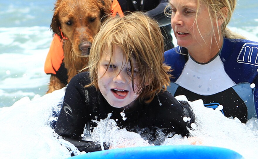 Ian McFarland surfs with Ricochet the dog.