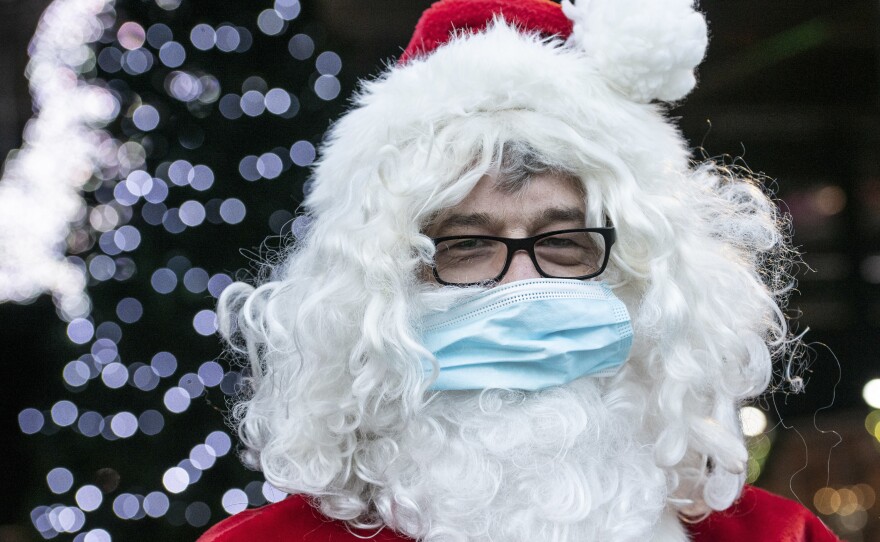 A Santa Claus in Germany wears a surgical mask in December 2020. If you're planning to take the kids to see Santa this year, experts say it's safest to keep everyone's masks on.