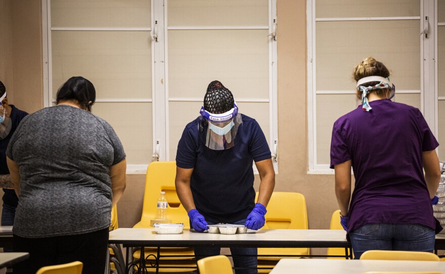 Cafeteria workers packed food to go on the first day school lunch rooms were allowed to open nearly two months after the start of Puerto Rico's lockdown.