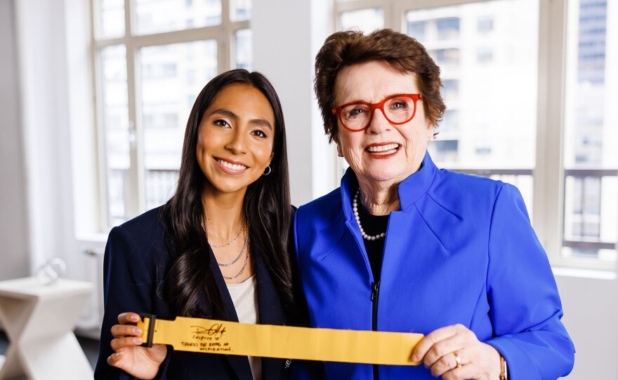 Billie Jean King and Diana Flores showing off the flag used in a Super Bowl commercial.
