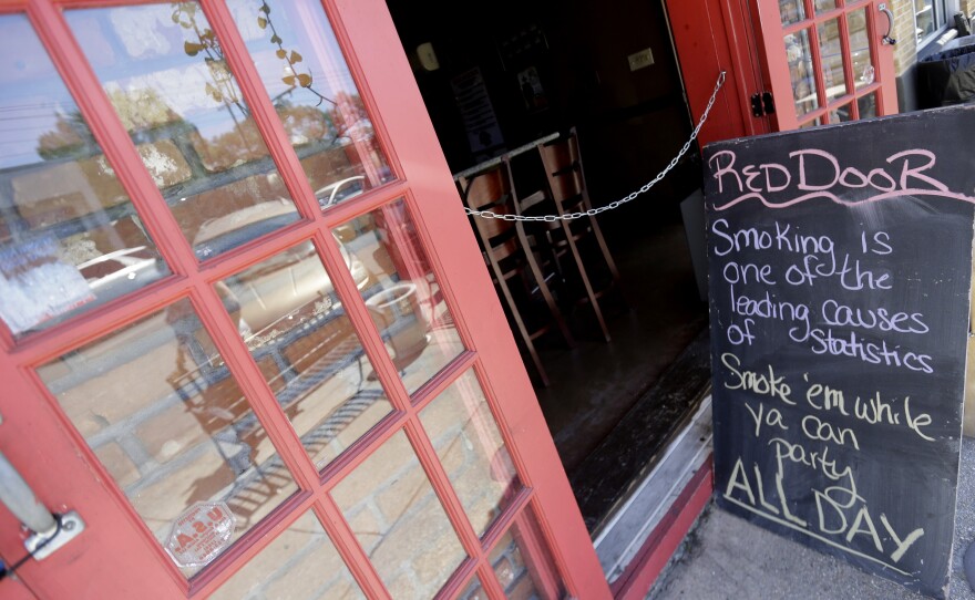 A sign warned about the impending smoking ban last weekend outside The Red Door lounge. Smoking became illegal inside bars and restaurants just after midnight Wednesday.