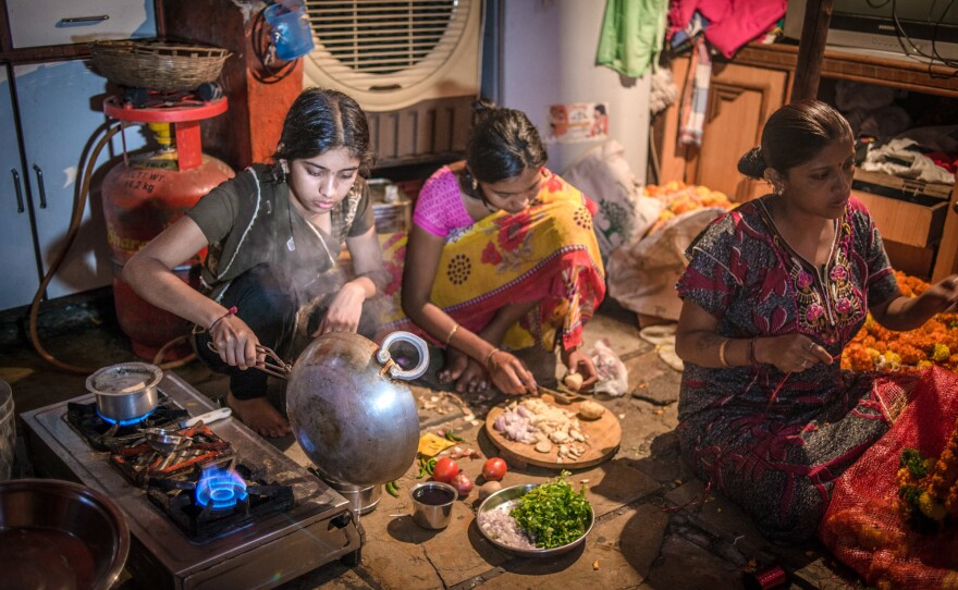 Anike's older sister (left, with a cousin) prepares a meal. Her mother, Rekha Sathe (right, stringing garlands for the family business), started teaching her daughter to cook at age 10 to prepare her for married life.