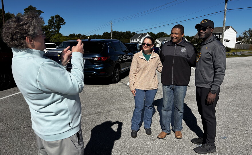 A volunteer snaps a photo of Democratic Rep. Don Davis with Onslow County Board of Commissioner candidates Rebecca Cooper and Michel Leandre Jr. outside an early voting location in Swansboro, N.C. Onslow is one of six counties added to North Carolina's 1st District in the latest redraw of congressional district lines.