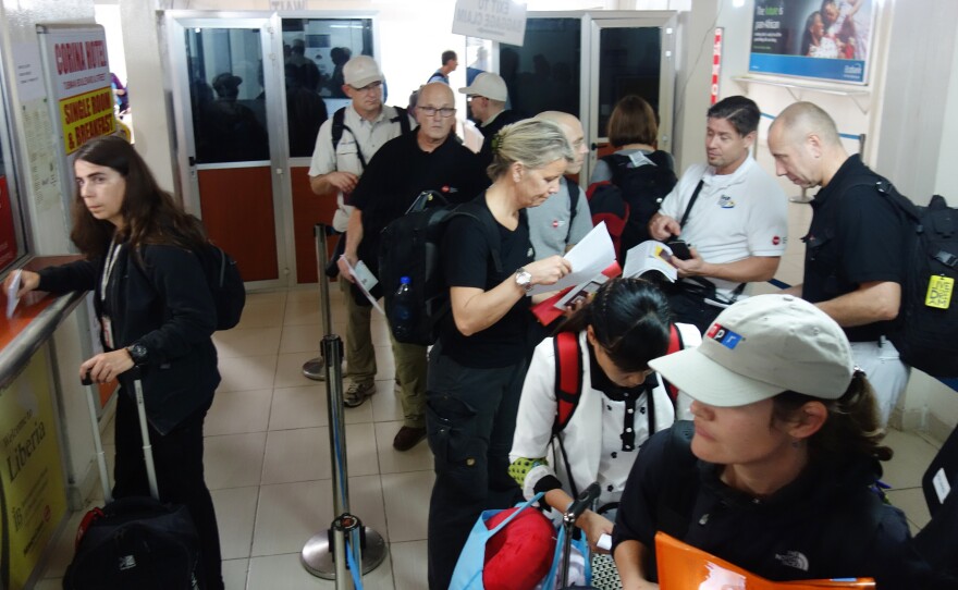 Our blogger Michaeleen Doucleff (in NPR cap) waits in line at Liberia's Roberts International Airport.