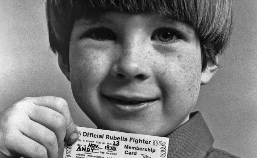 A little boy shows off the "Official Rubella Fighter" membership card and button he received after being immunized against the German measles. This public health campaign against the virus ran through the early 1970s.