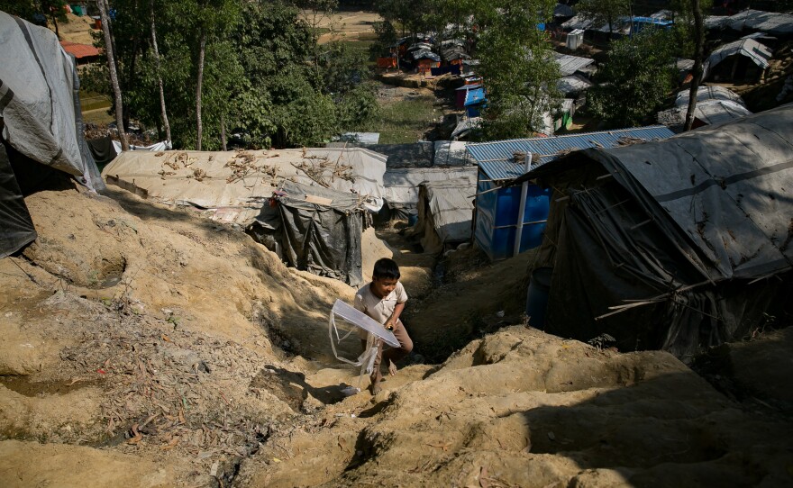 Khamal walks up the hill from his shelter with a kite he's just made.