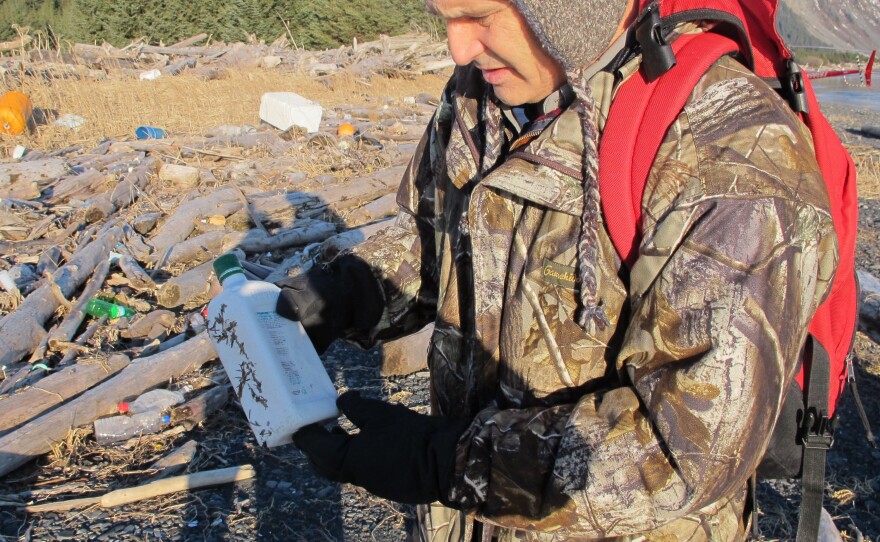 Chris Pallister examines a bottle of what he believes could be a household chemical item on Montague Island.