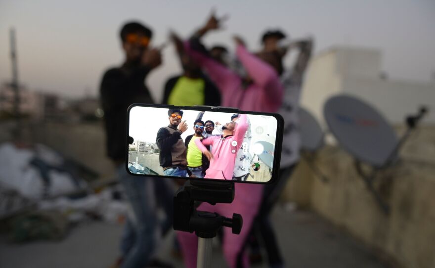 Youths perform in front of a cellphone camera while making a TikTok video on the roof of their residence in Hyderabad, India, in February. India's government has banned 59 Chinese-owned apps including TikTok.