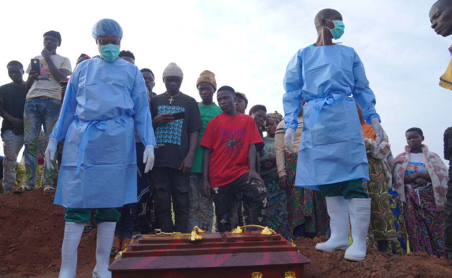 People dressed in protective gear prepare to lower into a grave the coffin containing the remains of 3-year-old Mave Mercienne, who died of Ebola, in Bunia, Ituri province, eastern Congo, Tuesday, Aug. 18, 2026.