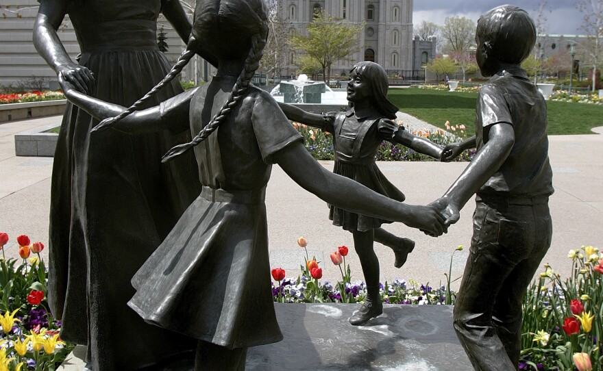 A statue representing womanhood — and women's role in raising children — is seen with the Mormon Temple in the background in Salt Lake City.