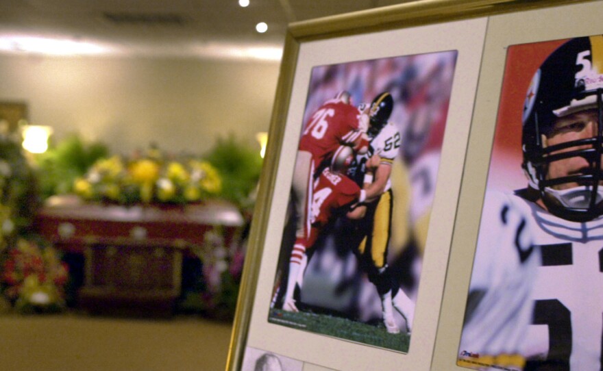The casket bearing the body of former Pittsburgh Steelers center Mike Webster is surrounded by flowers, after funeral services in Pittsburgh in September 2002. Mark Fainaru-Wada and Steve Fainaru, authors of <em>League of Denial</em>, point to Webster's autopsy as one of the most significant moments in the history of sports.